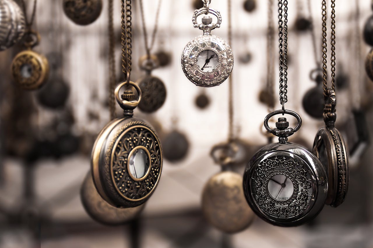 about-01 Close-up of antique pocket watches with intricate designs hanging in a blurred vintage setting.